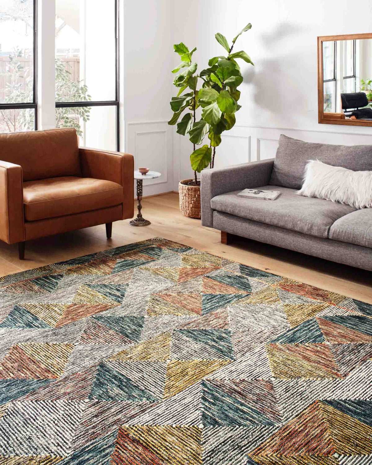 Geometric hooked rug in a living room: teal, tan, rust and blue abstract diamond chevrons.