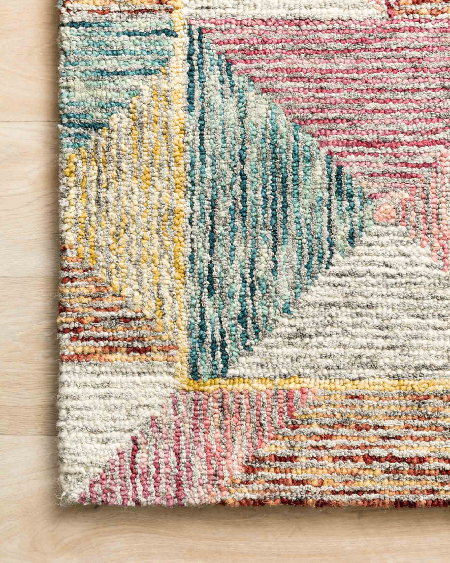 Close-up of hooked area rug corner with textured multicolor geometric lines