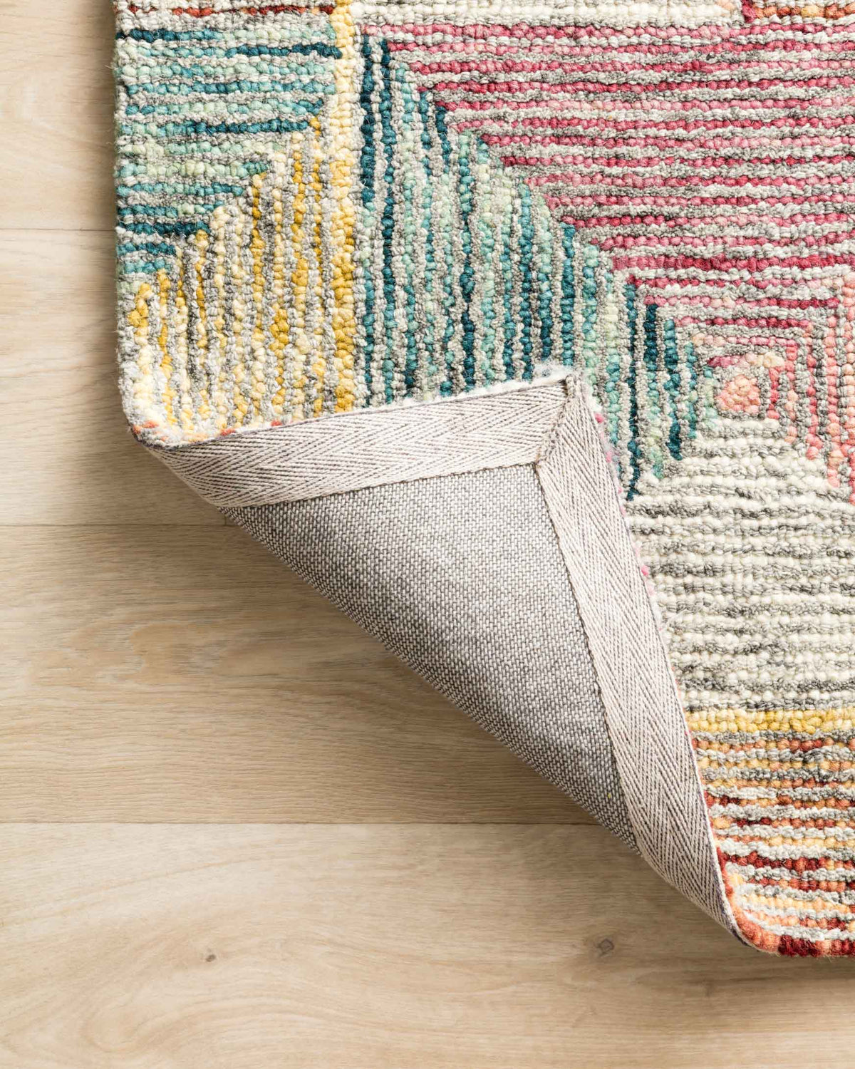 Hooked area rug edge with visible backing along the underside