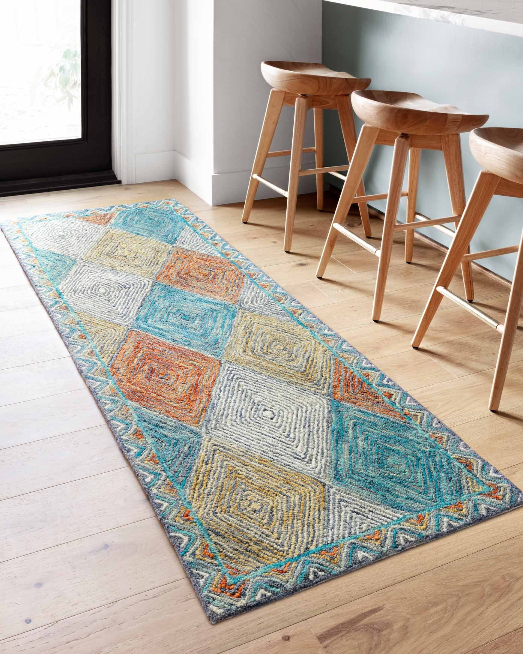 Rectangular hooked rug with multicolor chevron diamond design in teal, orange, and cream