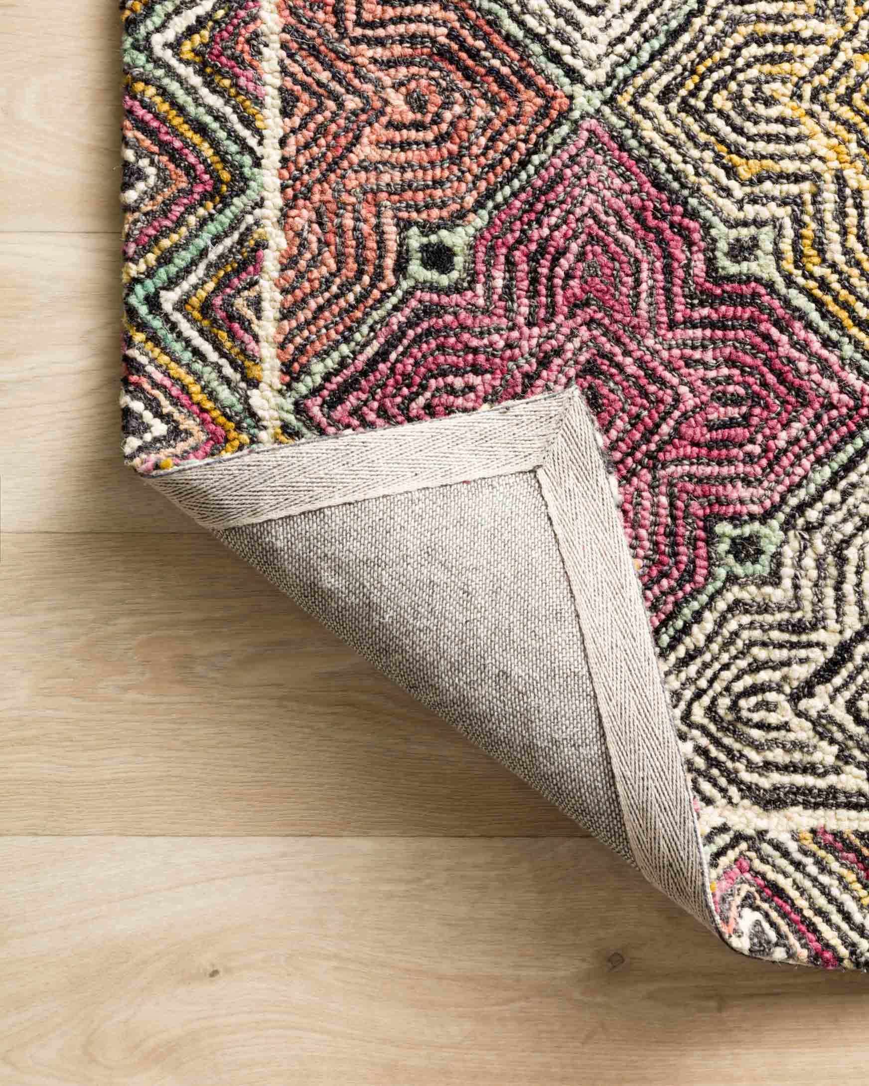 Hooked rug edge detail showing patterned face and backing fabric at the corner.