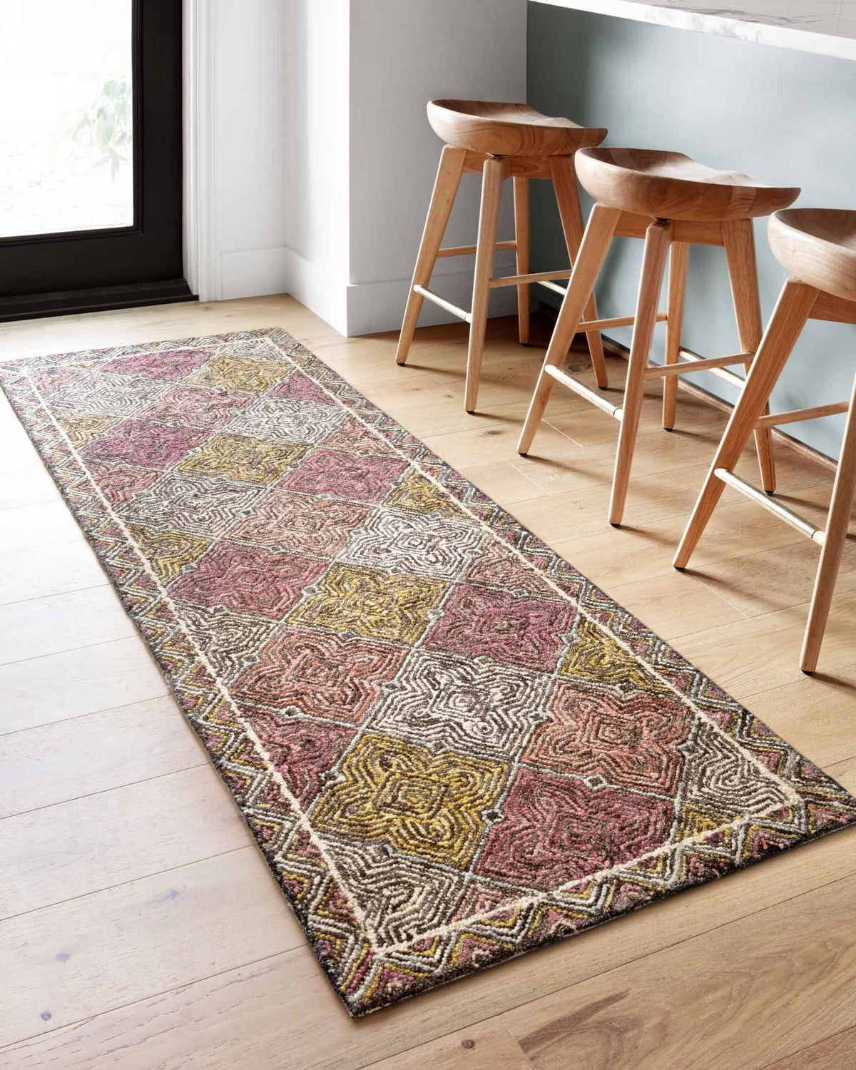 Runner-style hooked rug with geometric patterns in cream, charcoal, maroon, and yellow
