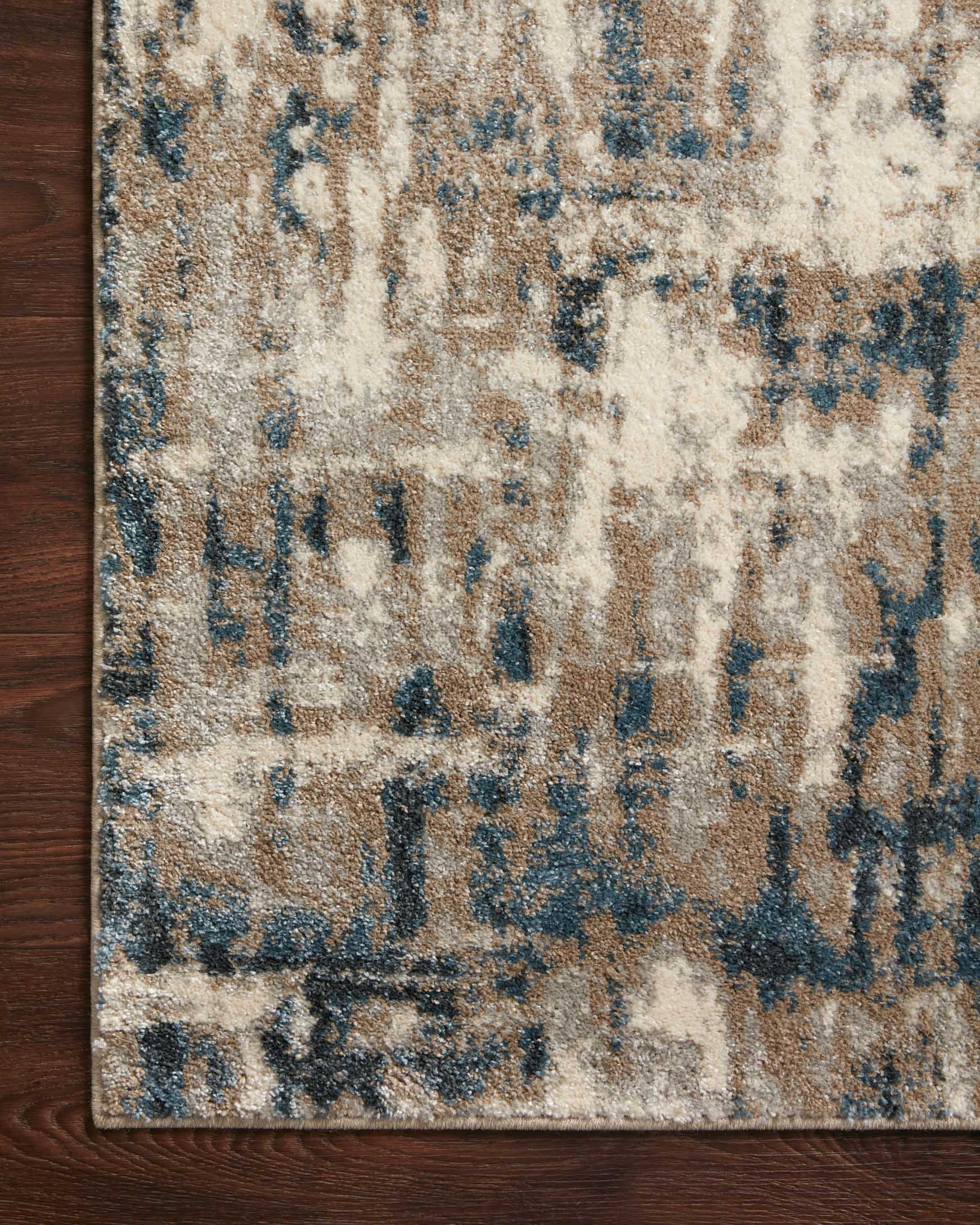 Top view of distressed abstract rug with blue specks and light stone background