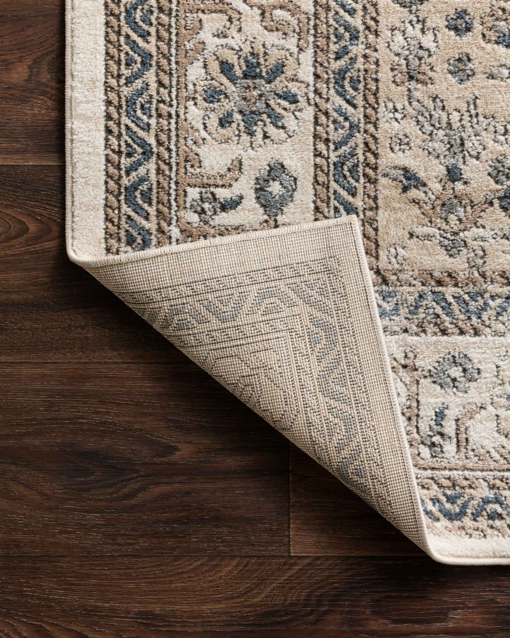 Oatmeal and ivory rug corner showing low-pile weave and blue-gray motif