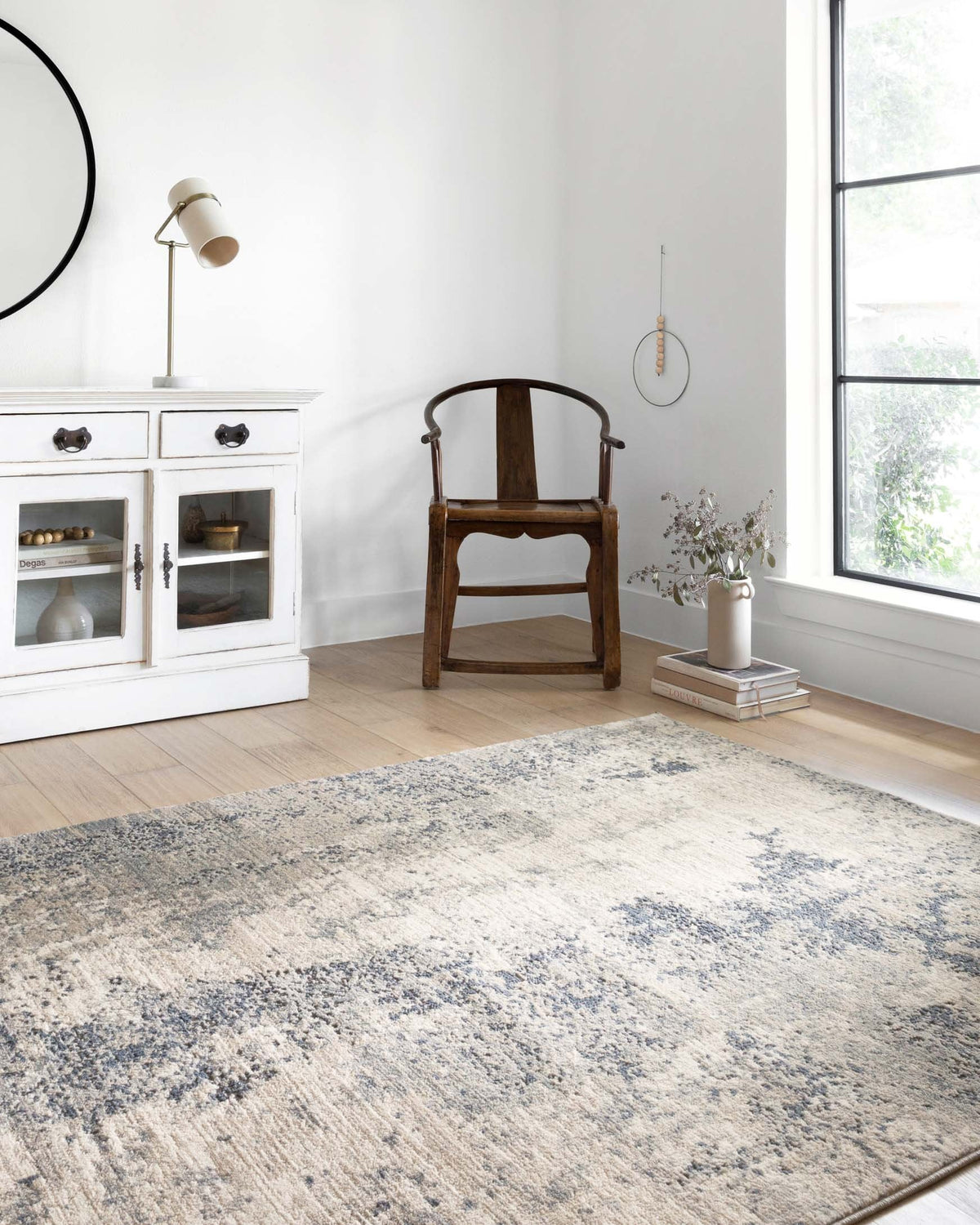 Power-loomed area rug in natural cream with denim-blue abstract speckles, shown laid out