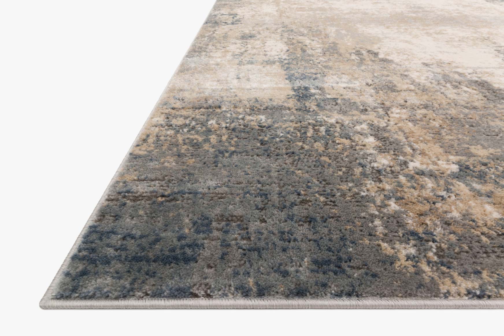 Ivory and mist rug corner detail with distressed abstract pattern and blue-gray speckling.