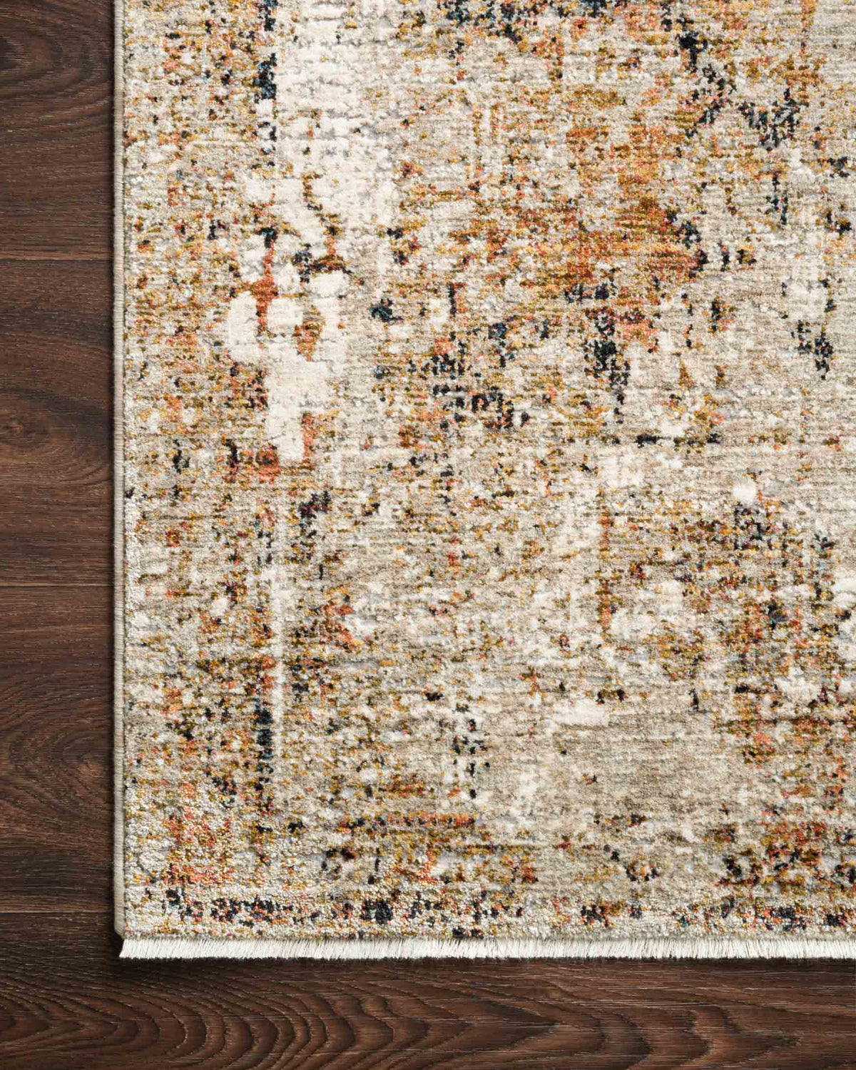 Close-up edge of area rug in taupe and gold with short fringe and textured distressed texture