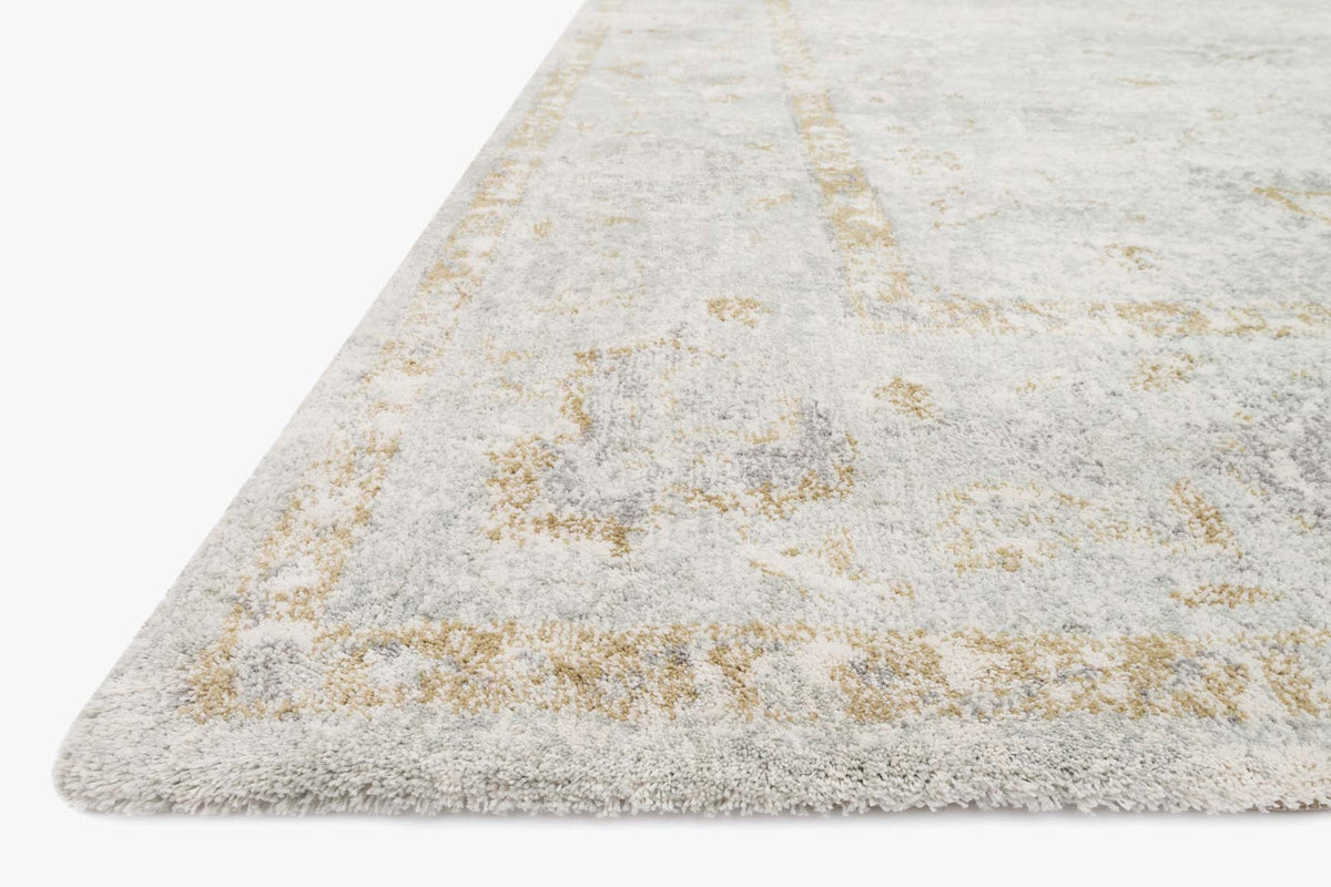 Power-loomed area rug corner, light gray with gold distressed overlay and textured pile