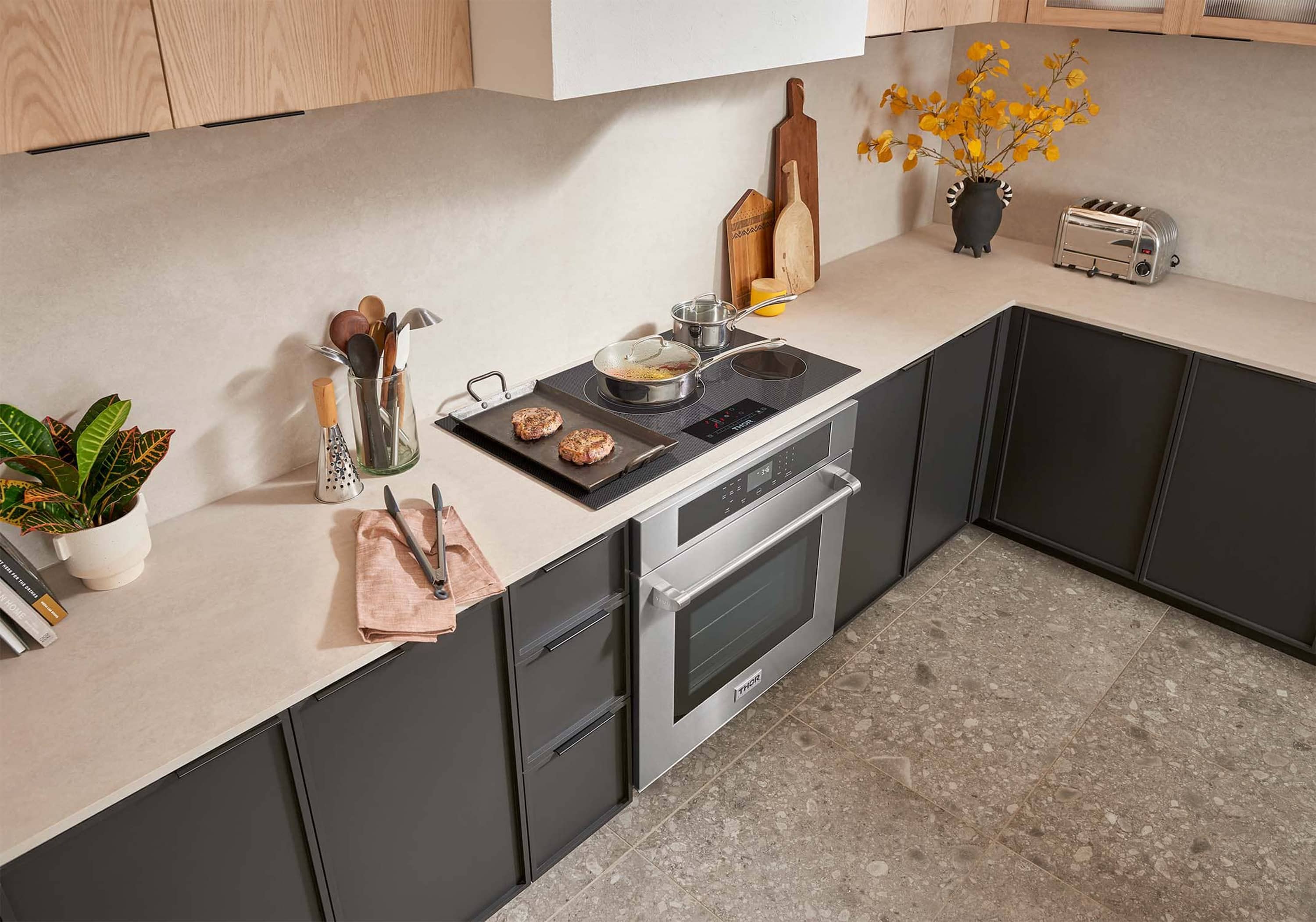 Black electric cooktop with burner rings and oven below on a modern kitchen run of cabinets