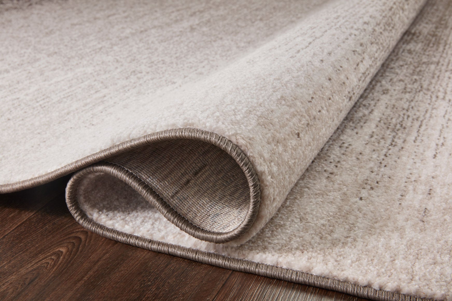 Textured taupe and dove rug edge with bound border and low-profile pile
