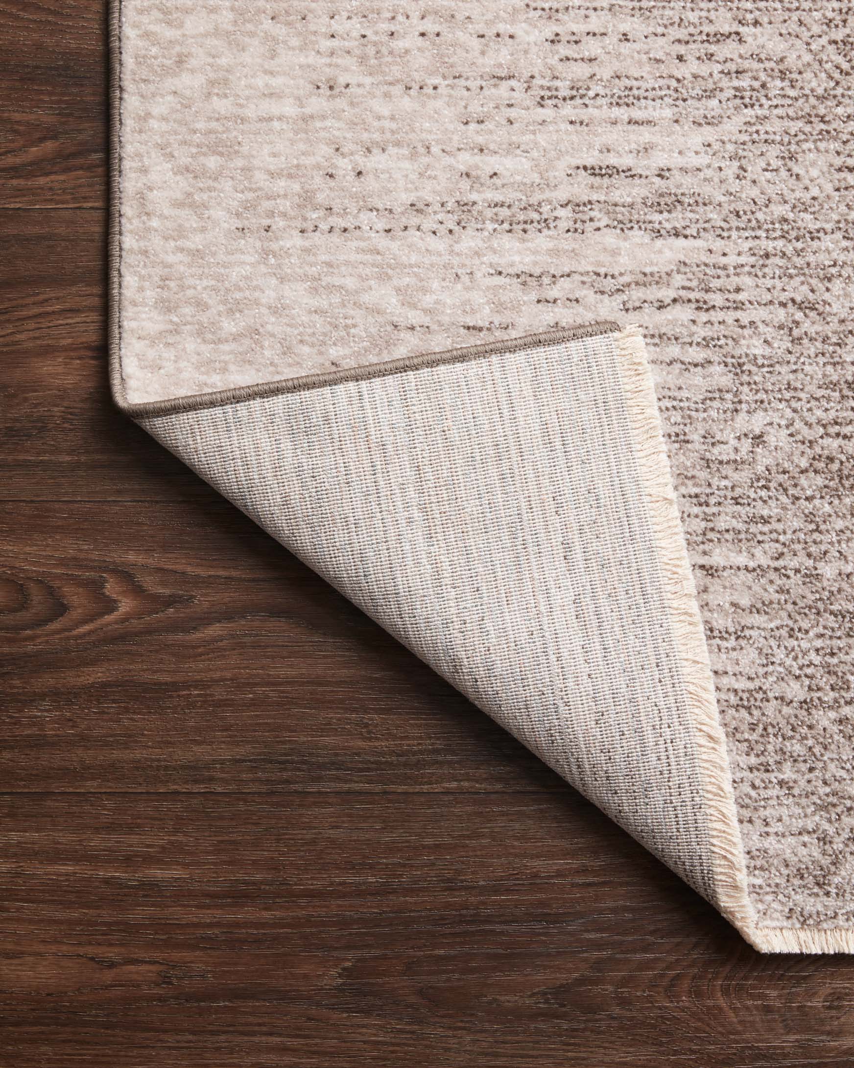 Power-loomed rug corner lifted to show textured underside in taupe and dove