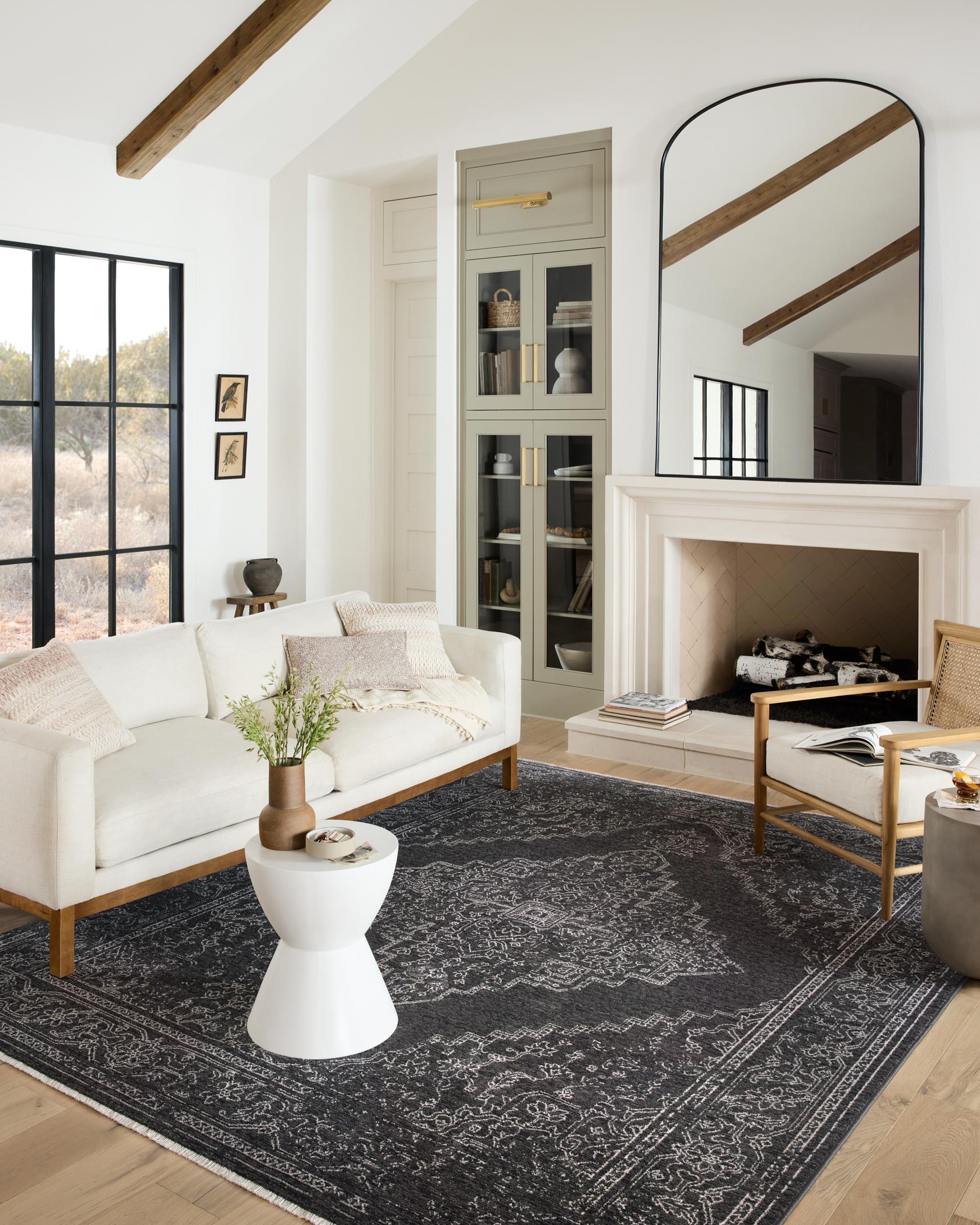 Charcoal and dove traditional power-loomed rug styled under furniture, showing bold geometric pattern.