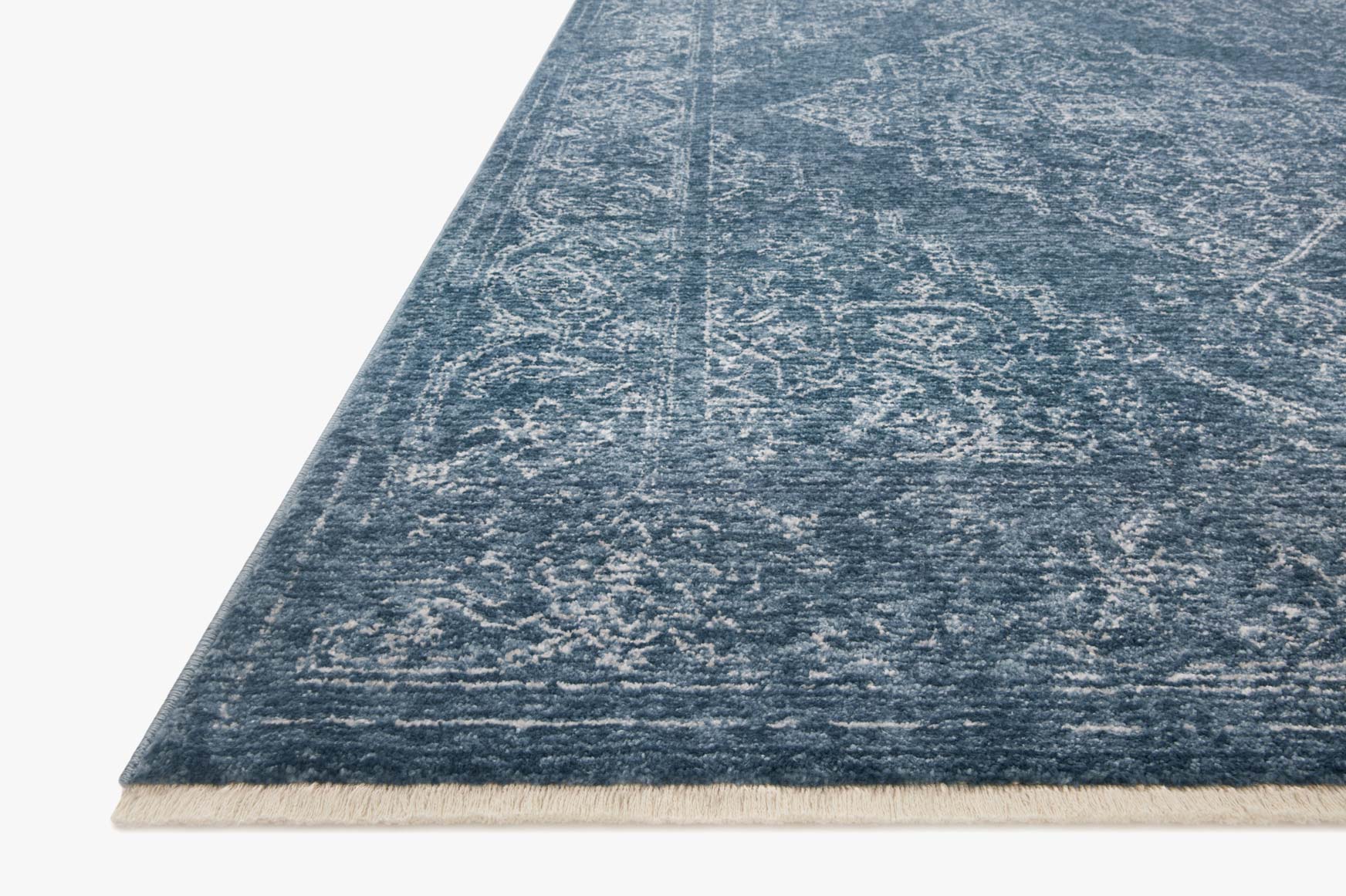 Denim blue patterned rug corner with light border and flat woven texture