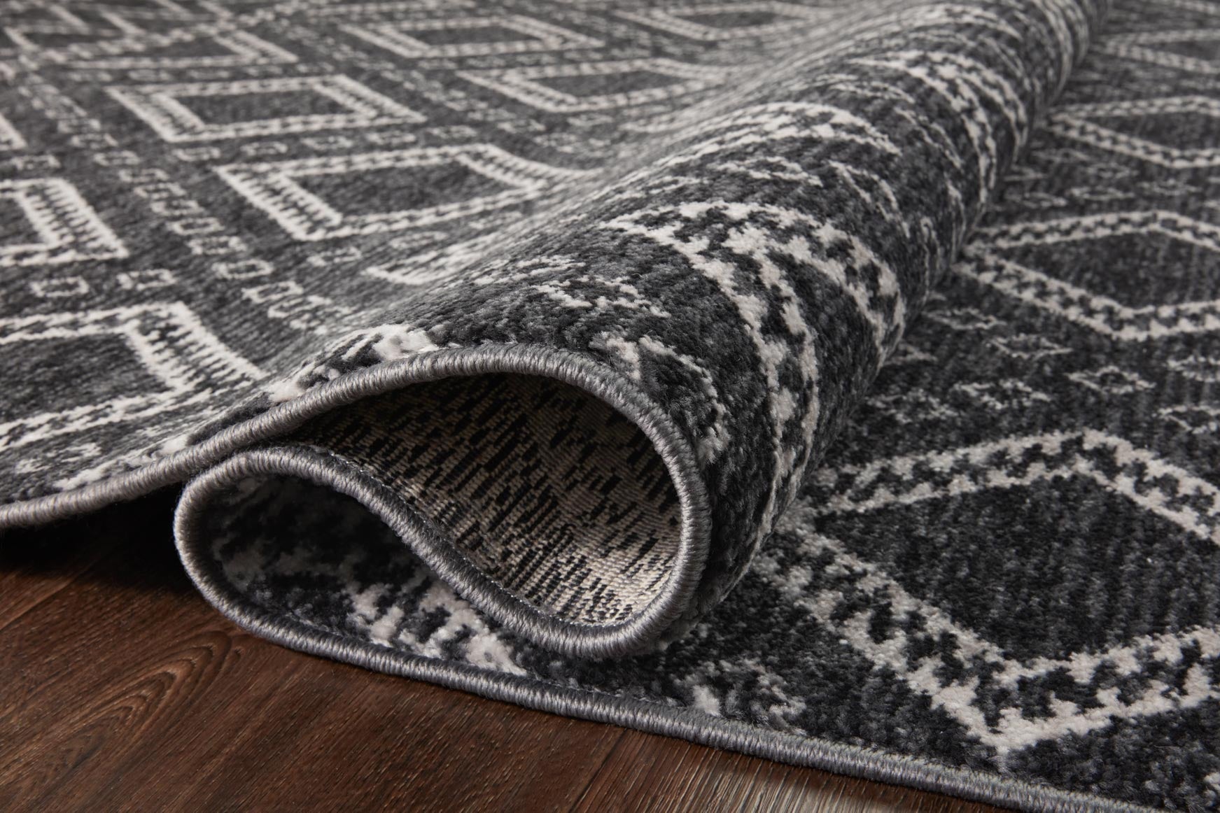 Charcoal rug with dove pattern, rolled edge showing flatwoven texture