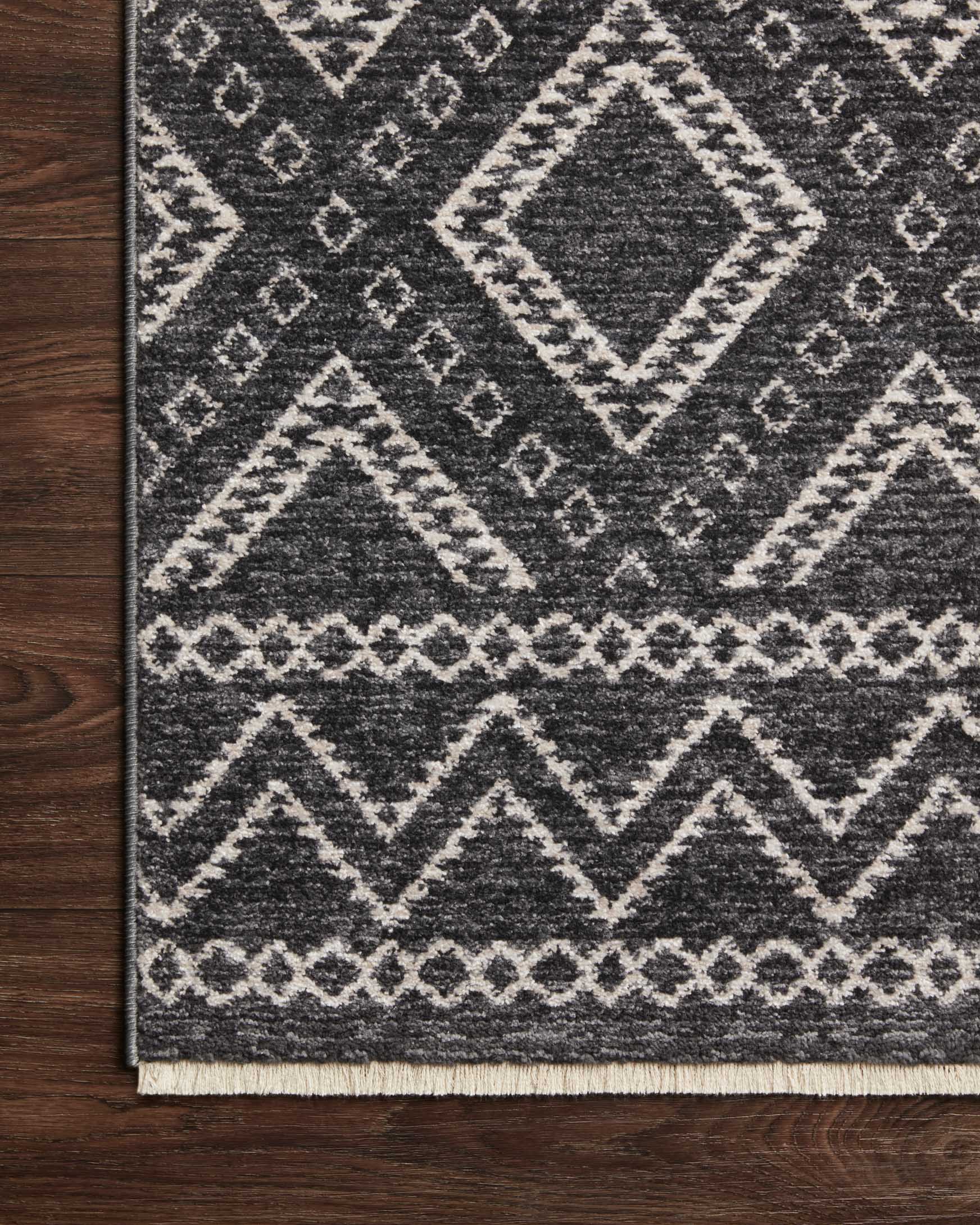 Charcoal rug with dove chevron and diamond motifs, flat edge on wood