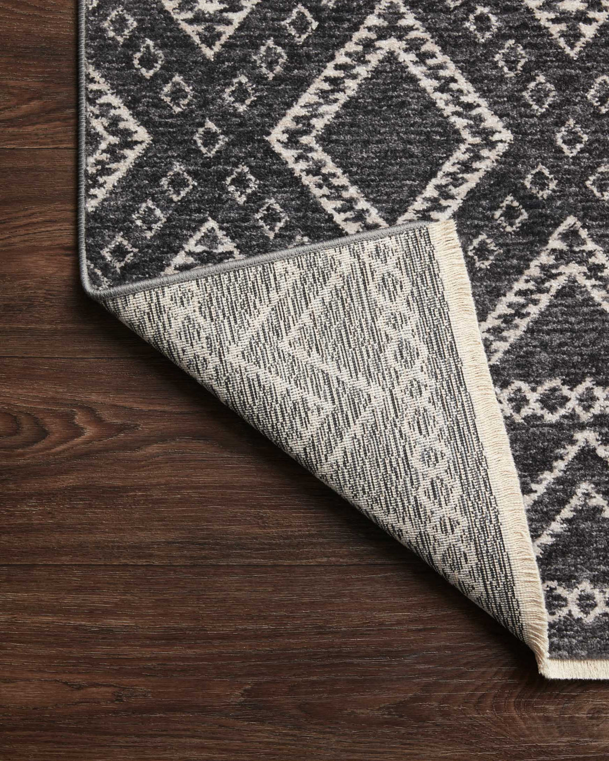 Charcoal rug with dove motifs, reverse side visible along folded corner
