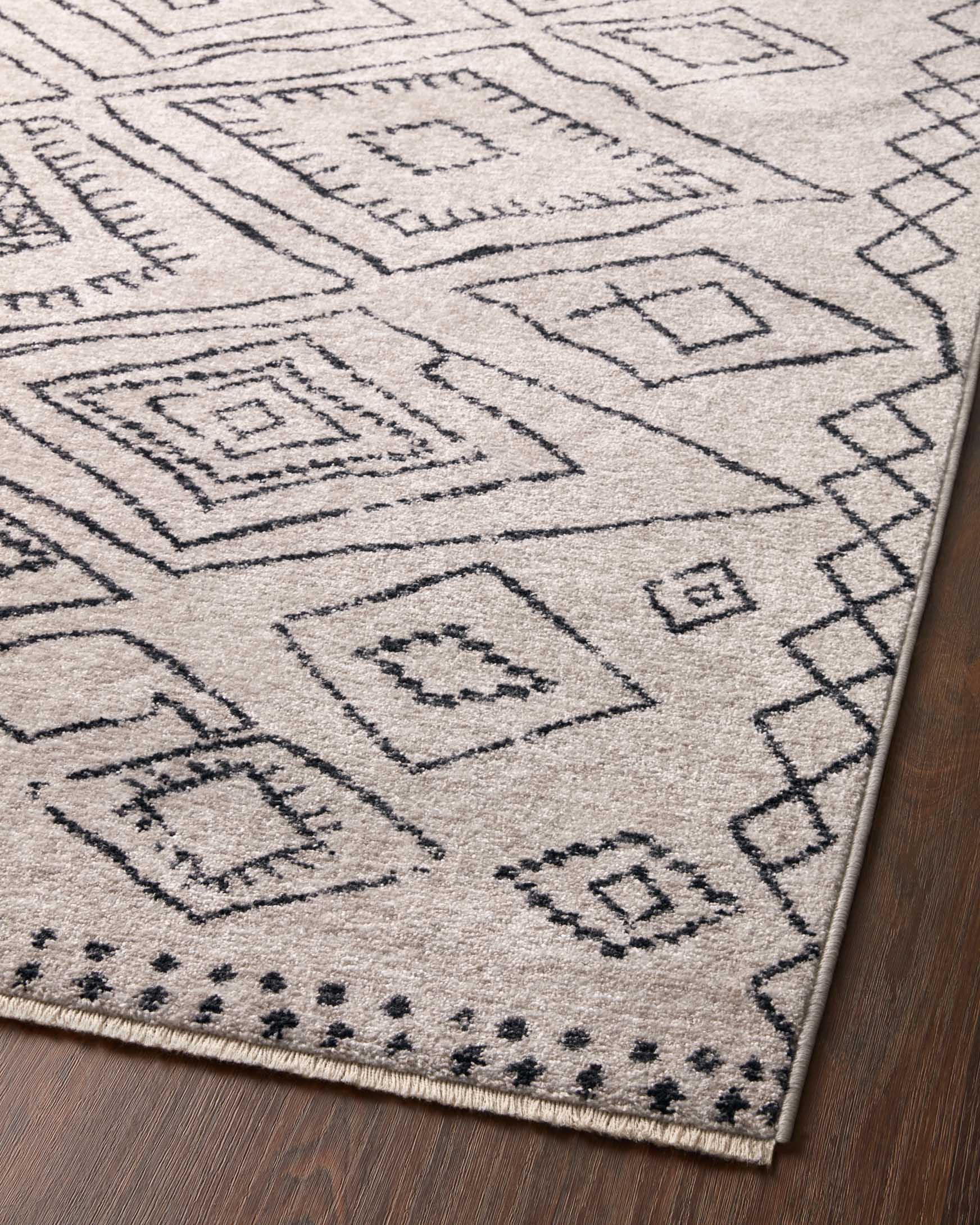 Dove-and-charcoal geometric rug corner with diamond shapes and dotted border