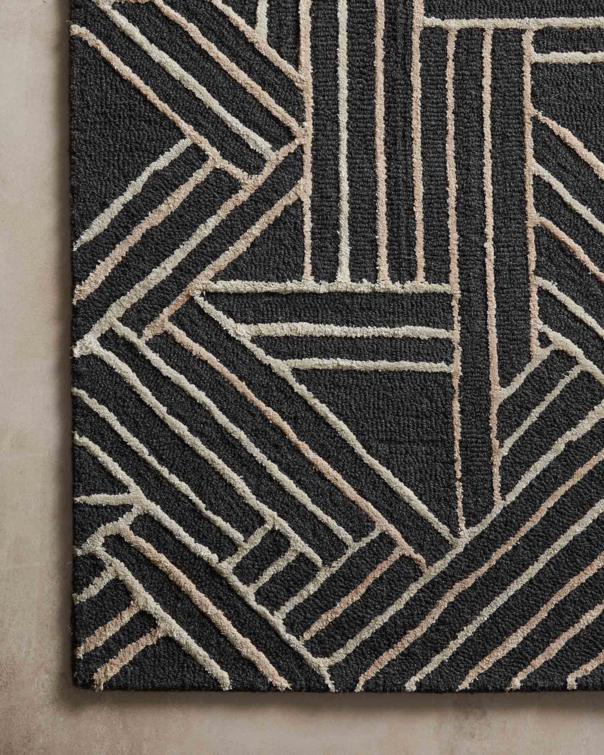 Charcoal hand-tufted rug close-up with intersecting geometric stripes in beige