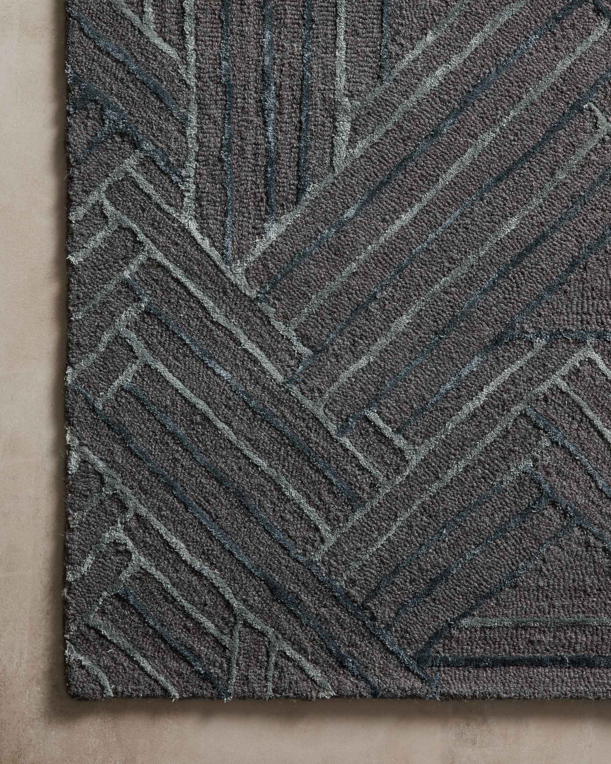 Close-up of geometric hand-tufted rug pattern in dark graphite with ocean-blue lines