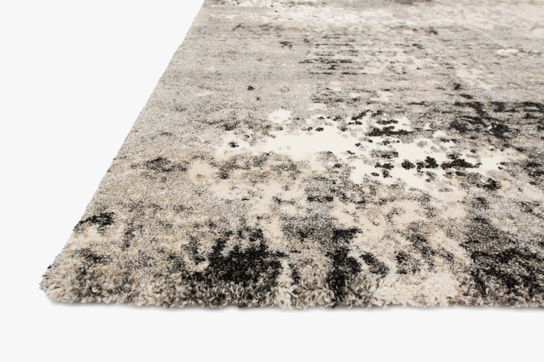 Grey abstract power-loomed area rug shown from angle, with speckled black and cream