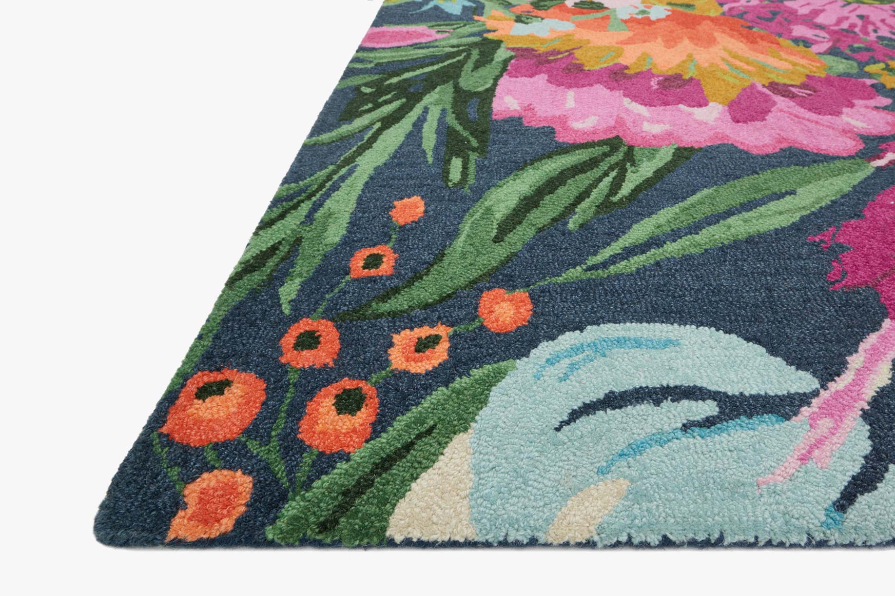 Hooked rug corner close-up with dark blue ground and large pink and orange blooms.