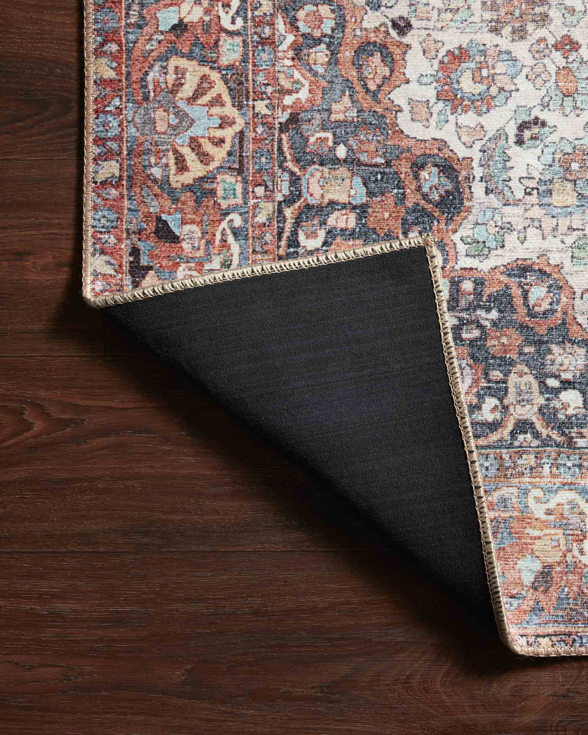 Traditional rug edge with layered border and multicolor motifs in red, blue, and cream.