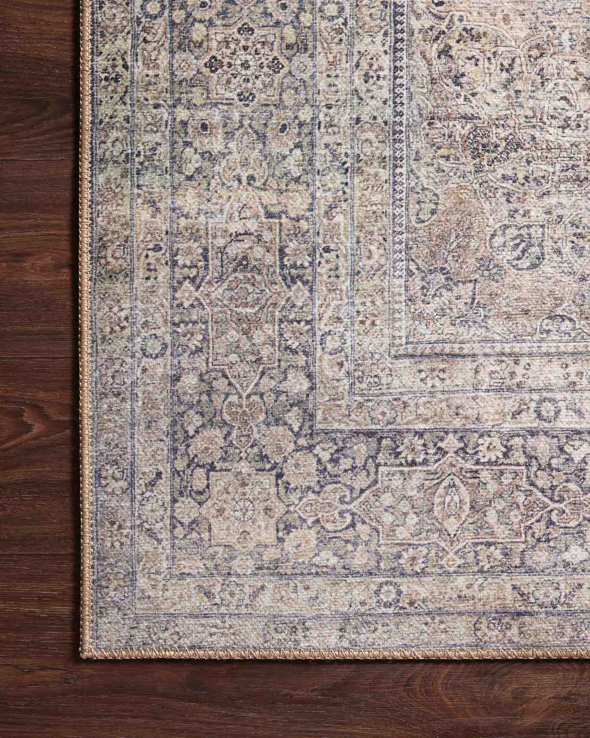 Edge view of silver and charcoal rug with intricate geometric and floral motifs.