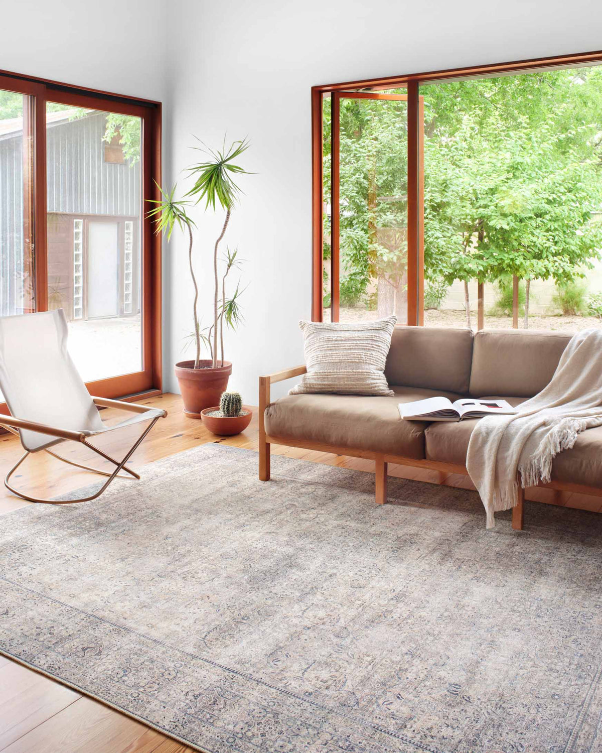 Silver and charcoal traditional area rug with ornate motifs, laid on light wood flooring.