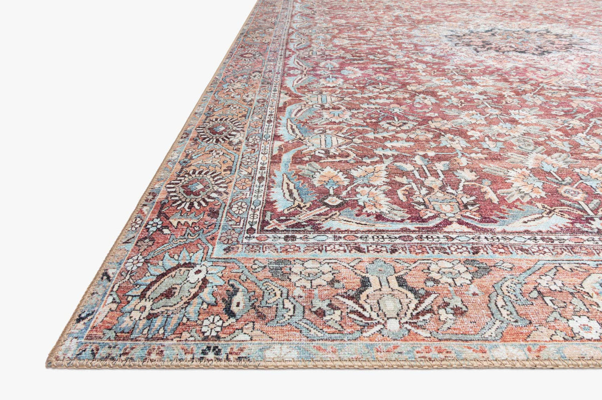 Corner detail of traditional rug with pink, teal, and cream ornamental pattern