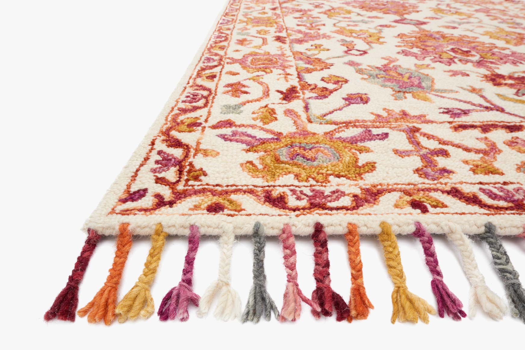 Corner detail of berry hooked rug with multicolor floral design and striped tassel fringe