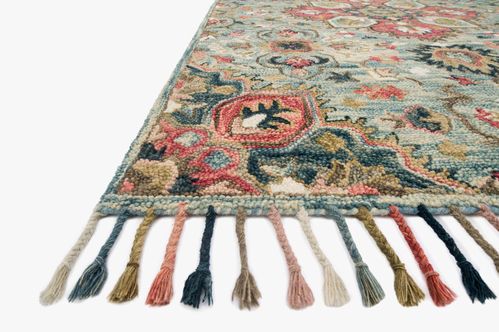 Light blue rug corner with multicolor hooked motifs and short fringe tassels