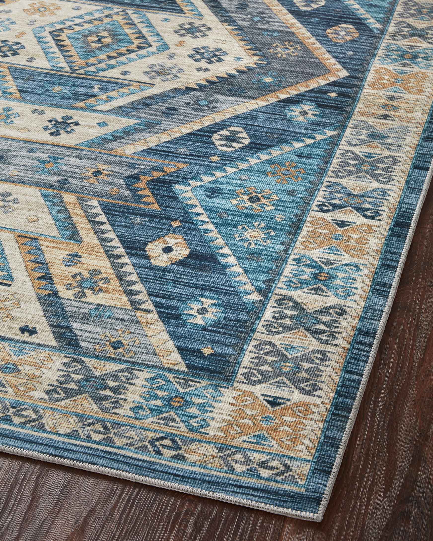 Diagonal view of blue and gold geometric rug with cream diamond and triangle motifs