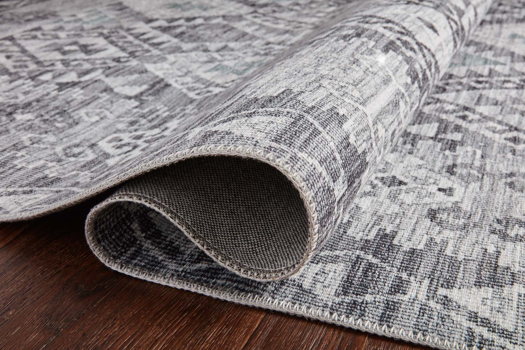 Charcoal and slate rug edge with tightly bound border and low-pile woven texture