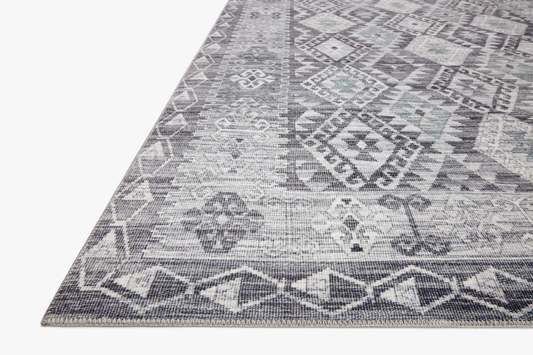 Corner view of charcoal and slate traditional power-loomed rug with geometric motifs