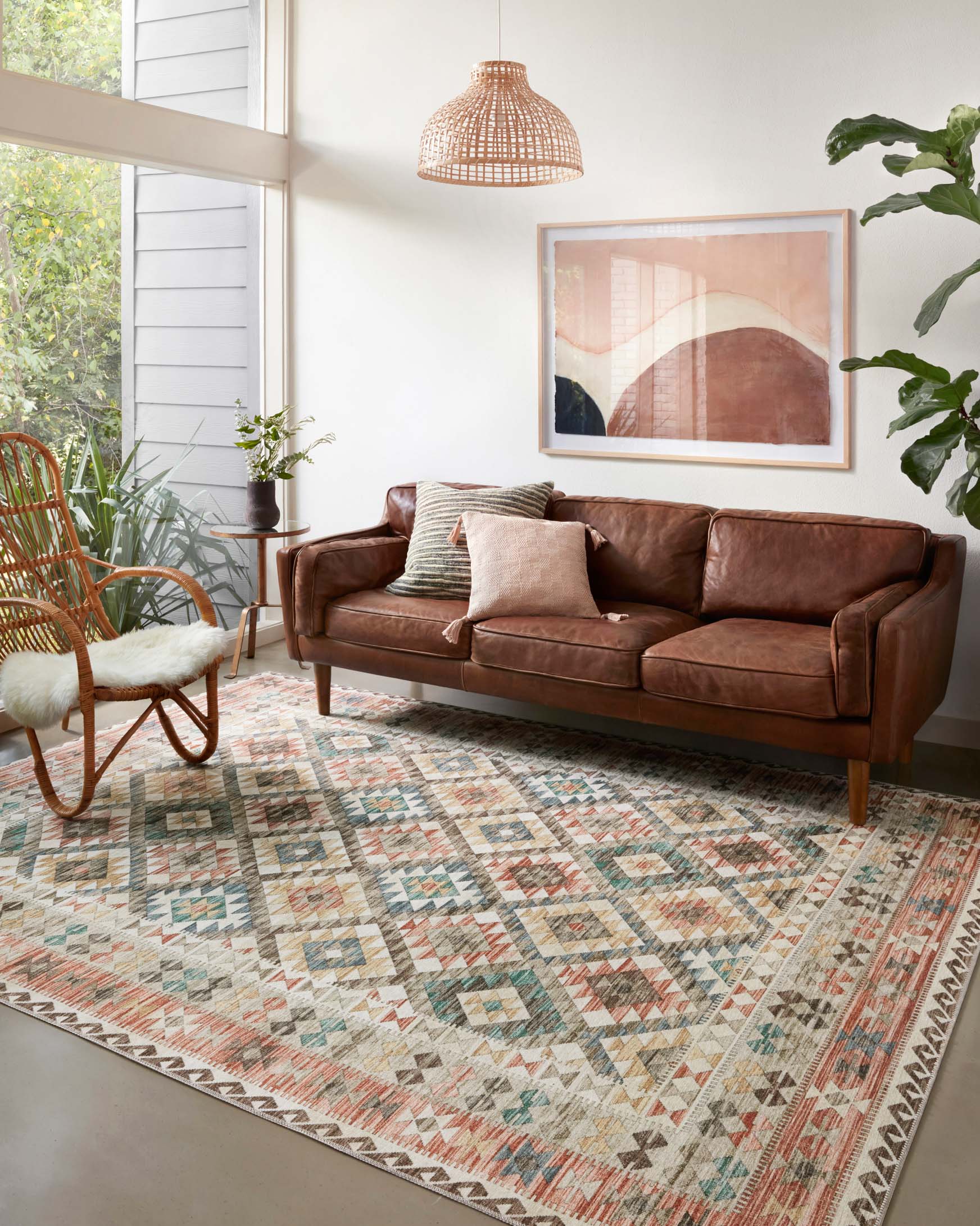 Geometric area rug with ivory, rust, teal, and gray tones on a hardwood floor.