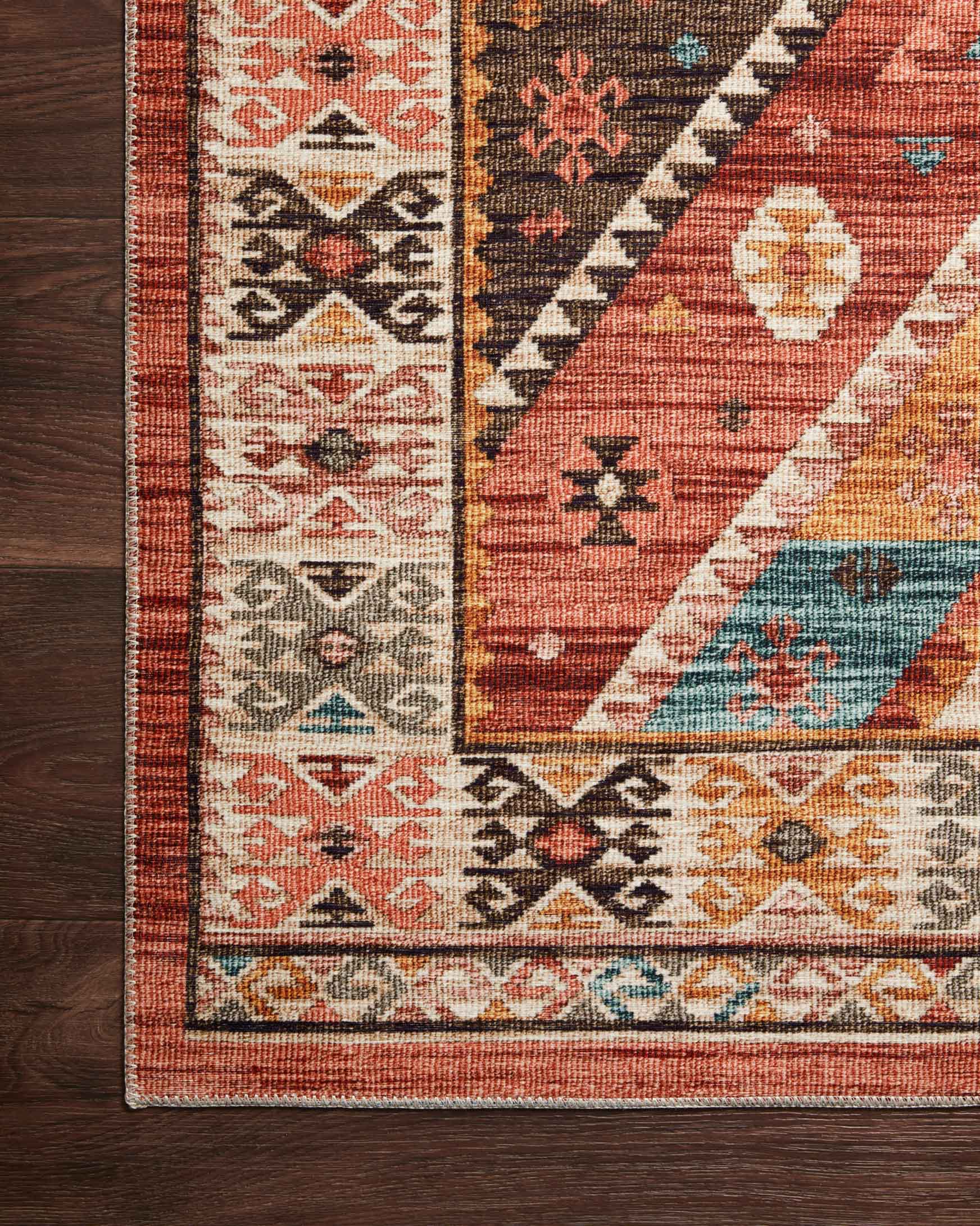Close-up of rug corner with red, teal, and beige pattern and dark border trim