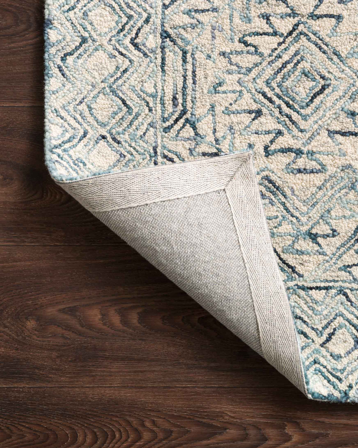Hand-tufted rug with folded edge, geometric diamond pattern in bluestone and ivory