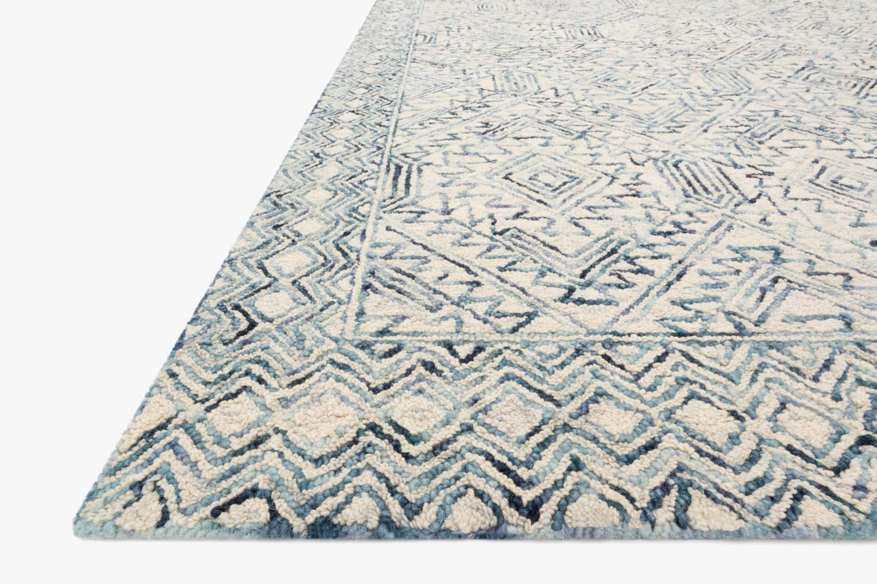 Hand-tufted rug corner with zigzag and diamond motifs in bluestone and ivory