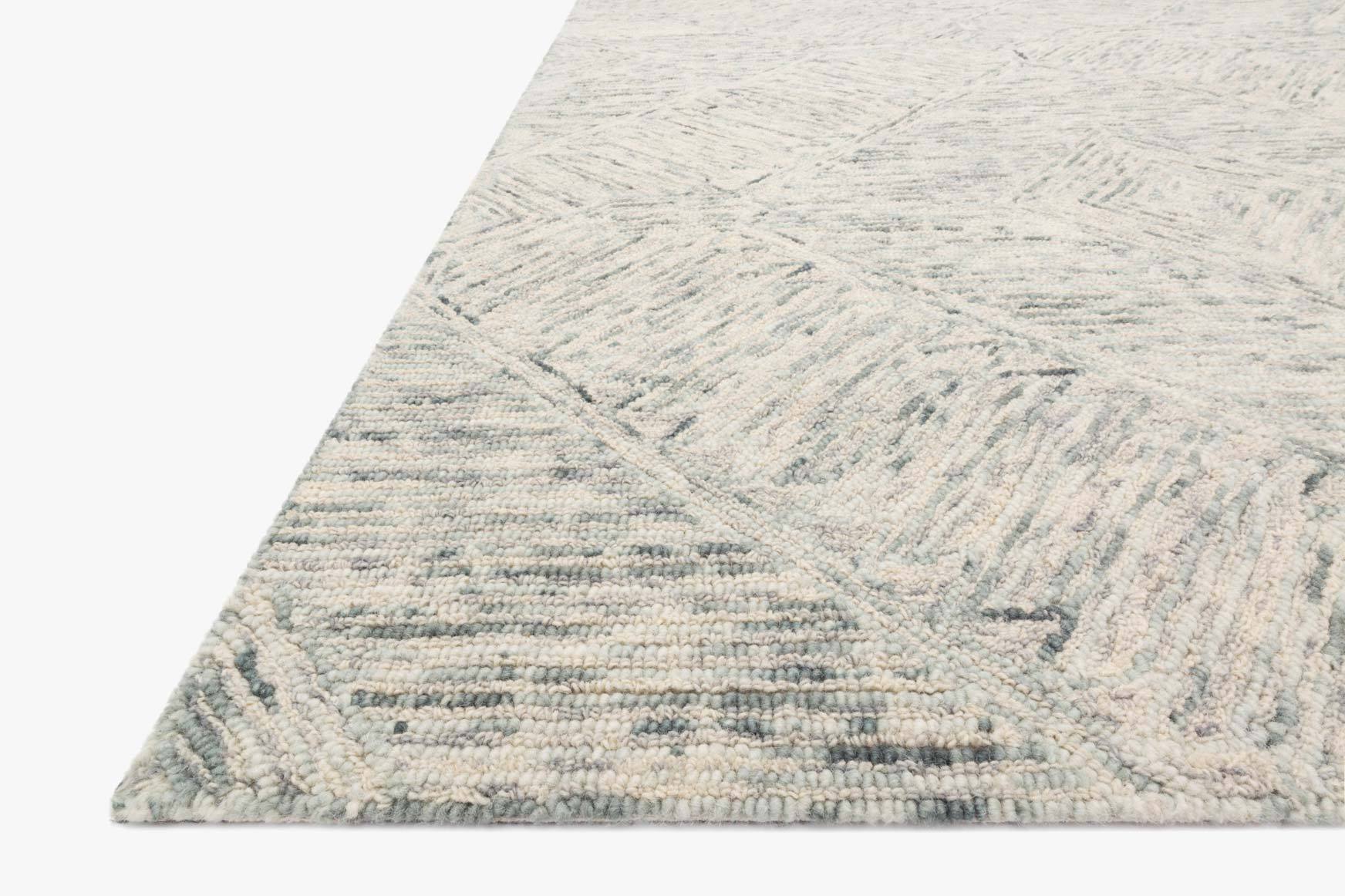 Sky-blue hand-tufted rug corner close-up with geometric motif and textured loop pile