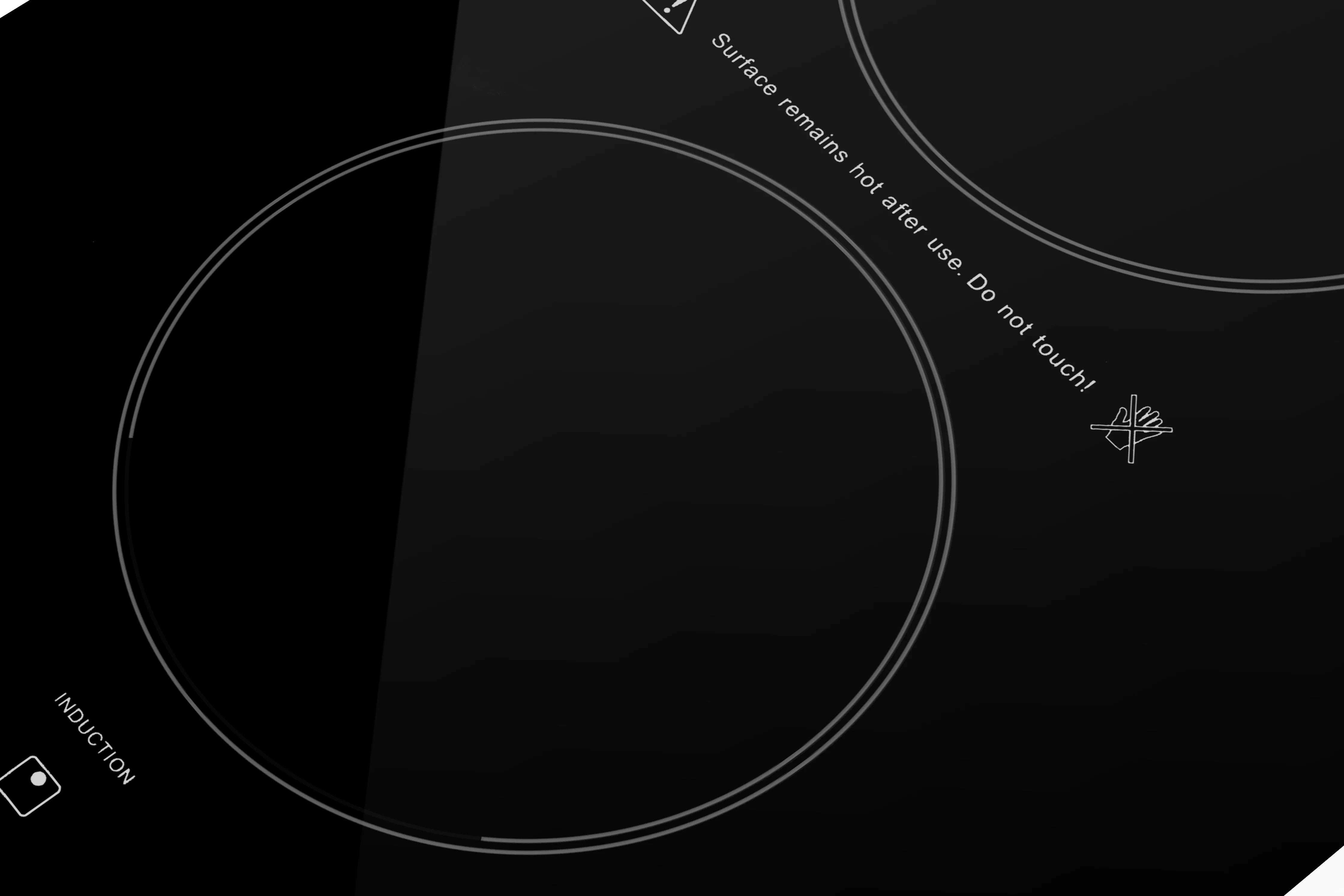 Close-up of black induction cooktop glass with circular heating zones and markings