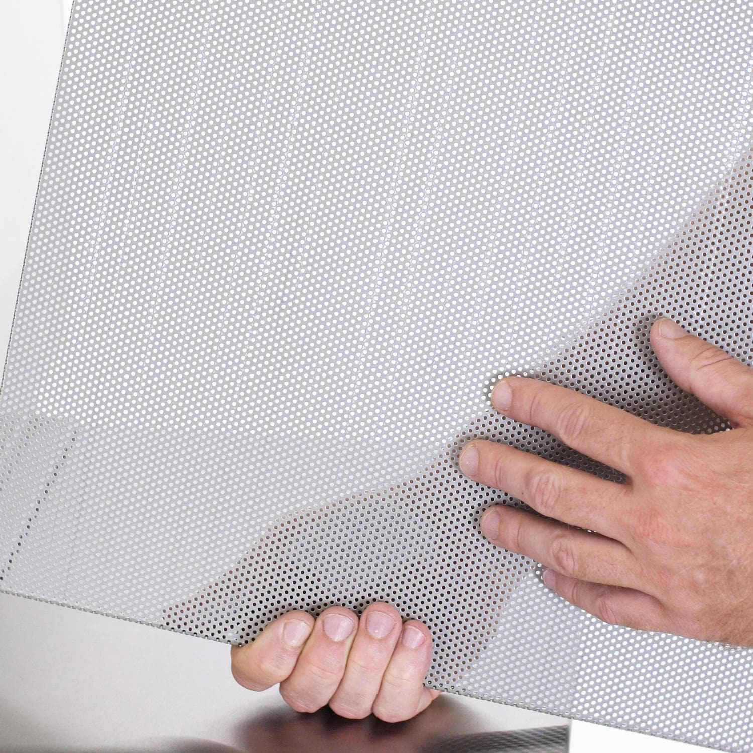 Perforated flame guard drip tray being pressed into place with both hands