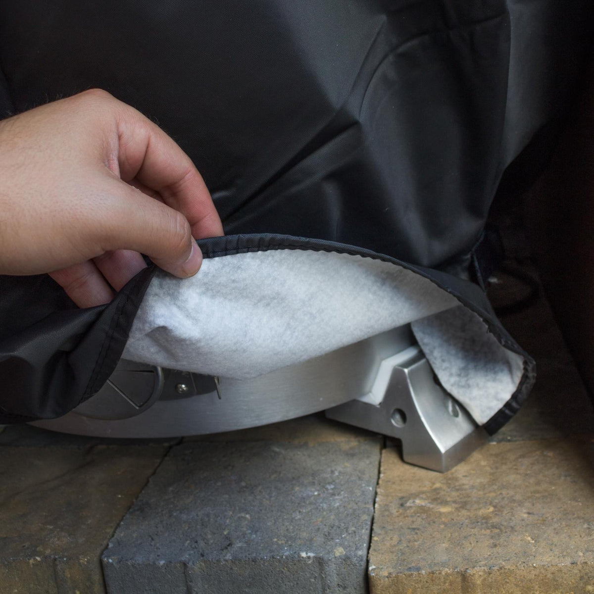 Black grill cover with gray lining; hand pulls open the front flap