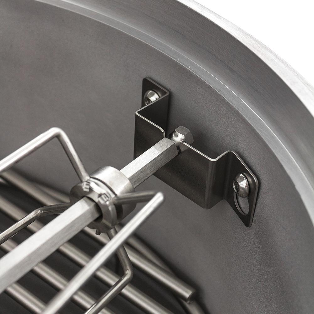 Stainless steel rotisserie spit with forks and wall-mount bracket on grill