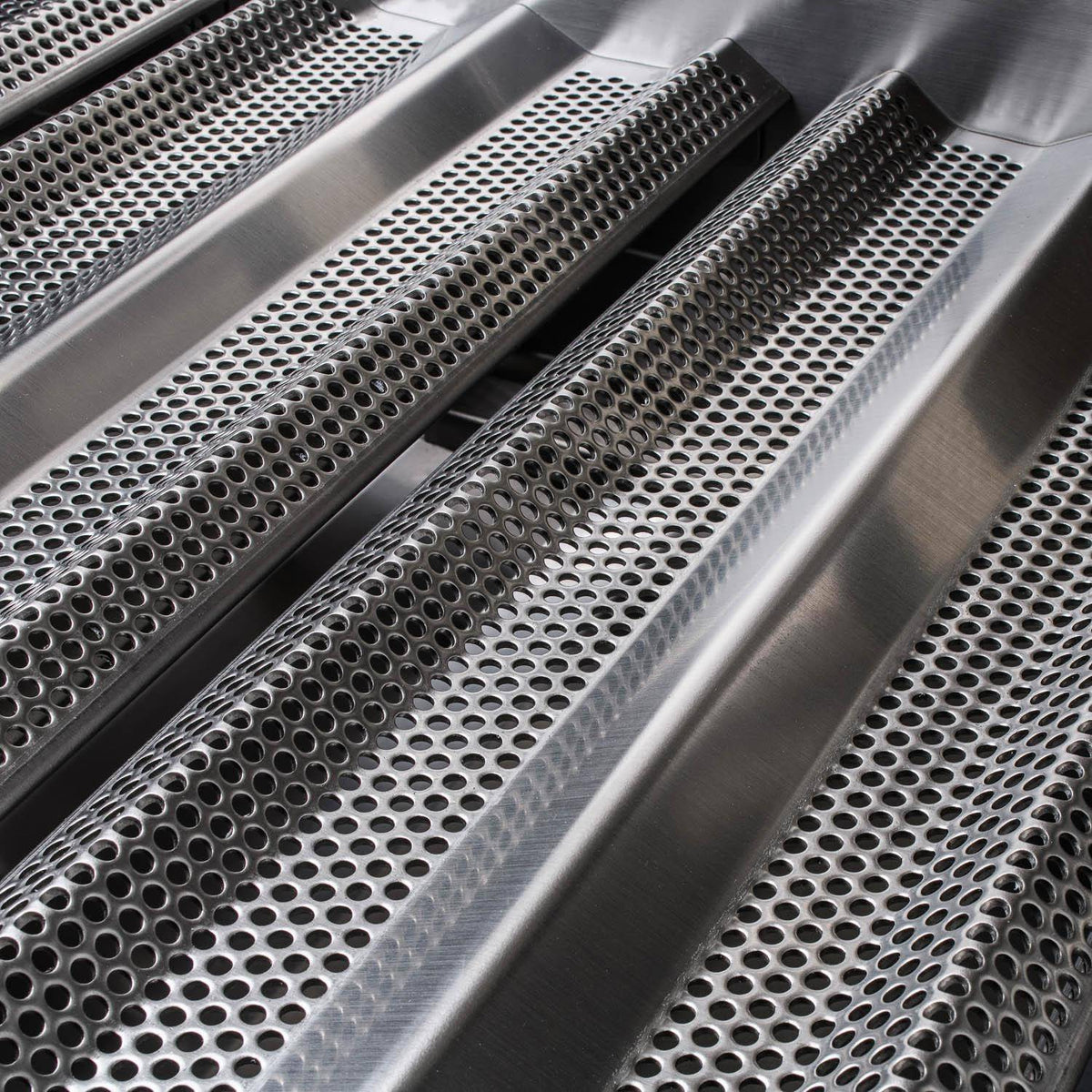 Stainless steel perforated cooking grates with burner channels