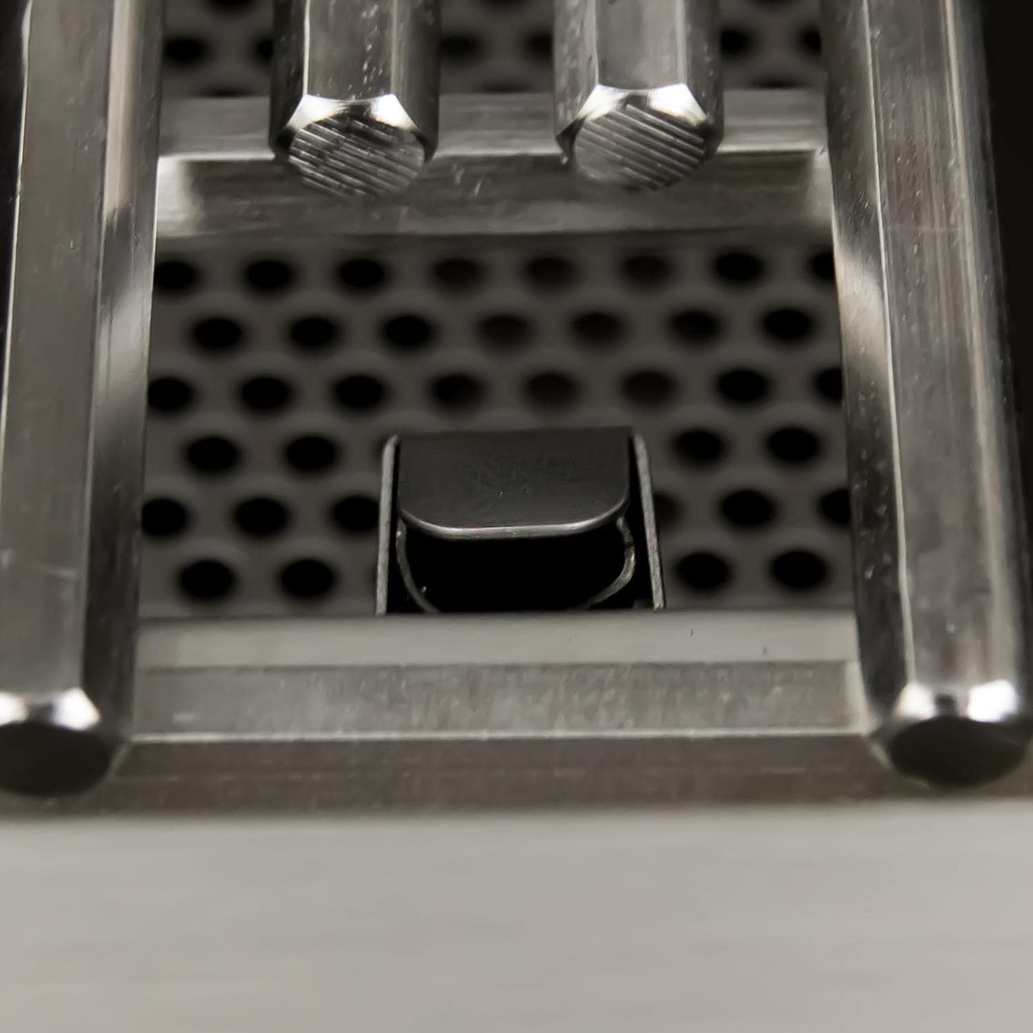 Stainless steel cooking area with perforated heat shield and small metal tray