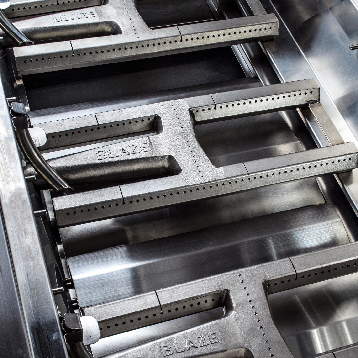 Inside view of stainless gas grill burners with Blaze branding and metal shields