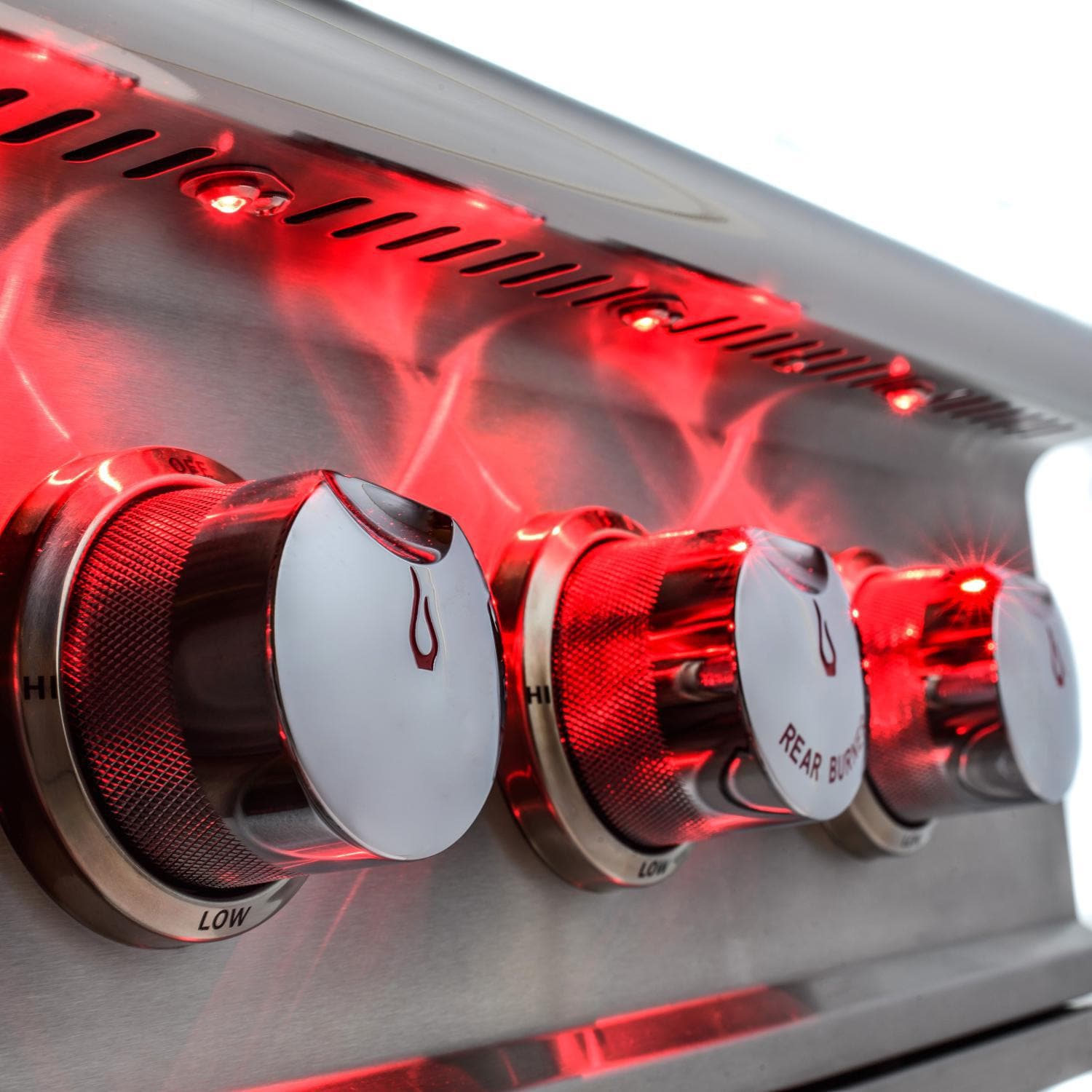 Gas grill burners glowing red behind stainless steel control knobs