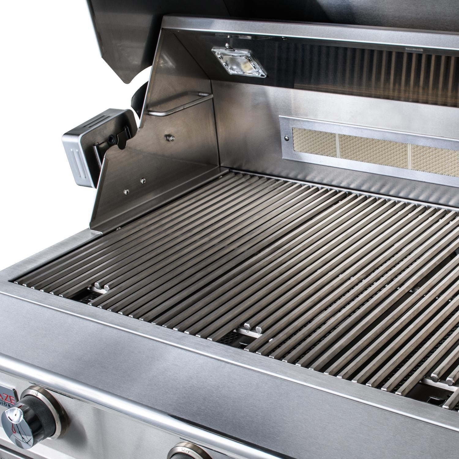 Stainless built-in gas grill open with ribbed cooking grates and warming area