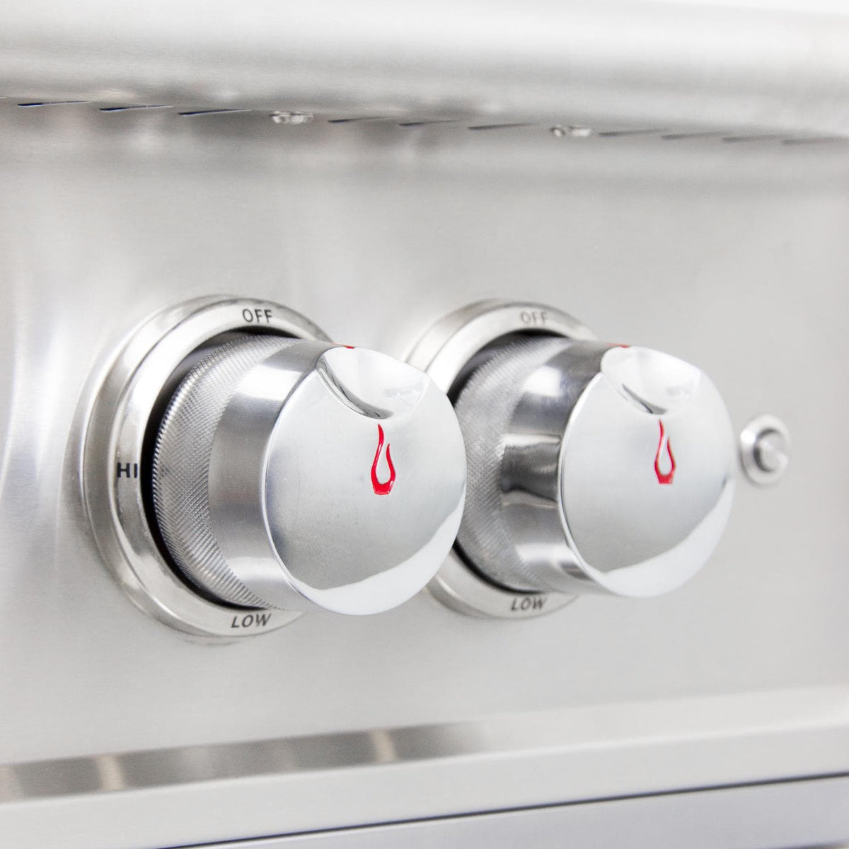 Close-up of stainless grill control knobs with OFF and LOW labels and red flame icons