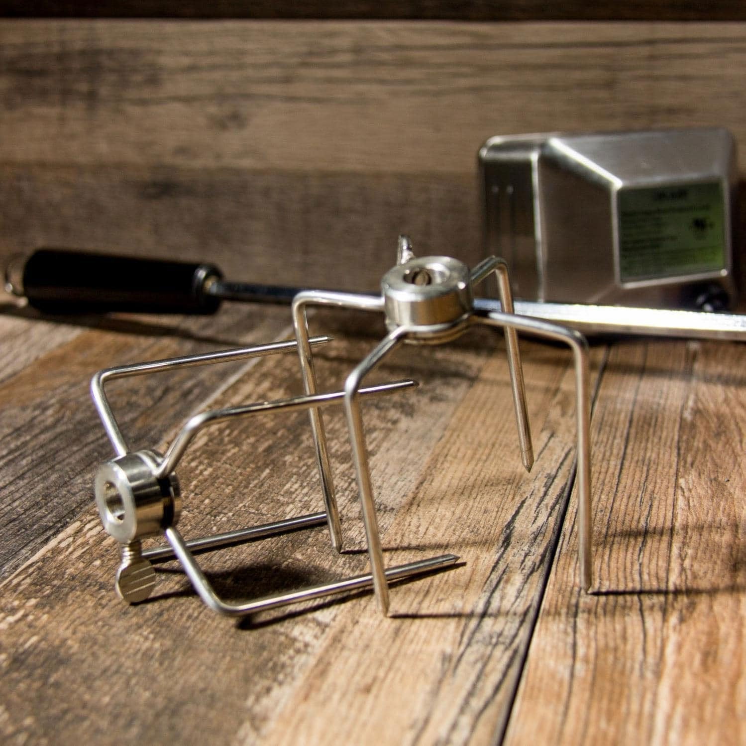 Rotisserie forks and spit frame with mounting hardware on wooden surface